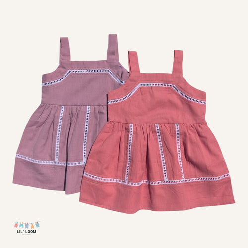 Two children's cotton strap dresses in pink and purple on a white background with 'LIL' LOOM' branding.