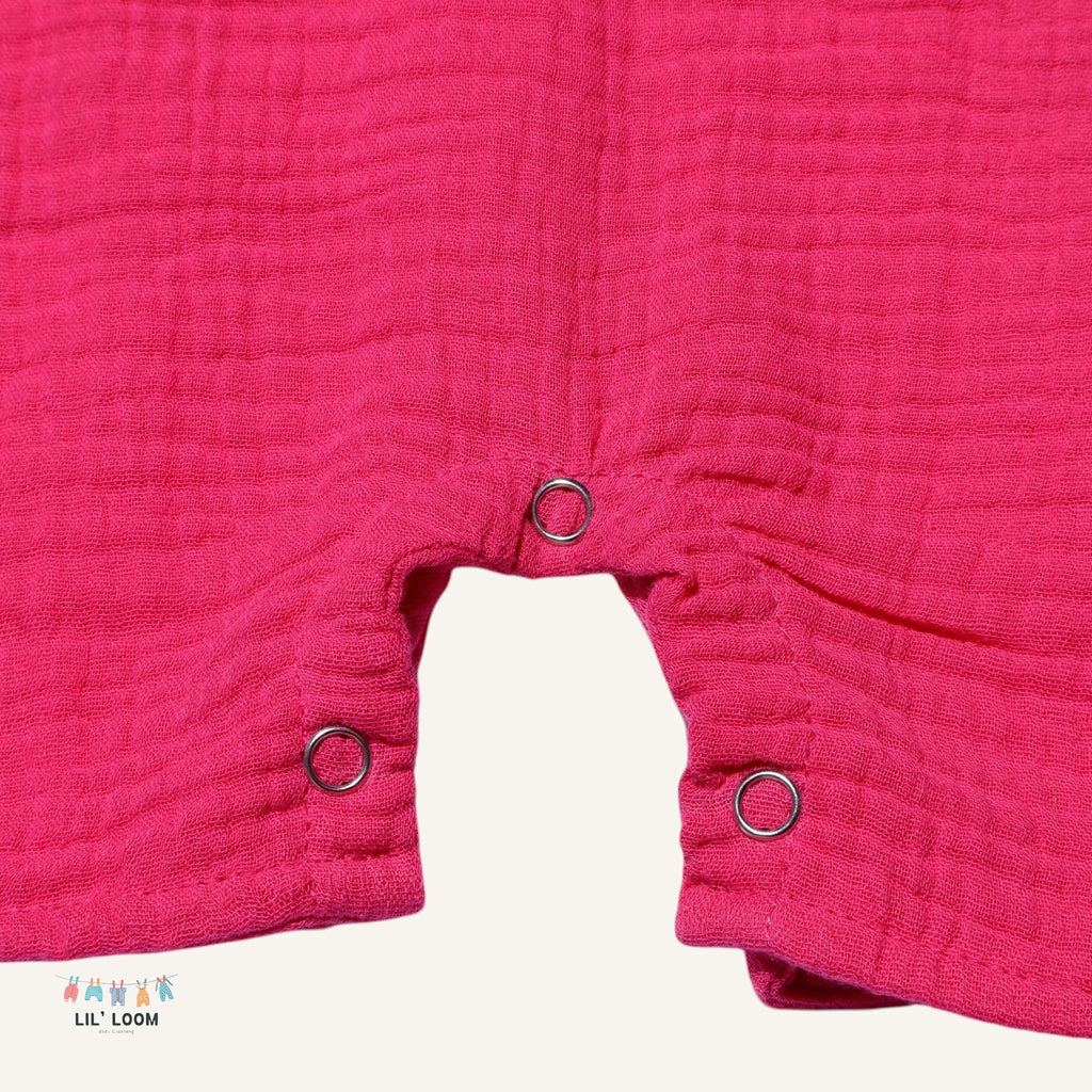 Close-up of a pink muslin fabric romper clasps, featuring the brand 'LIL' LOOM'.