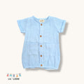 Light blue baby muslin romper with buttons and two front pockets on a white background, featuring the brand 'LIL' LOOM'.im