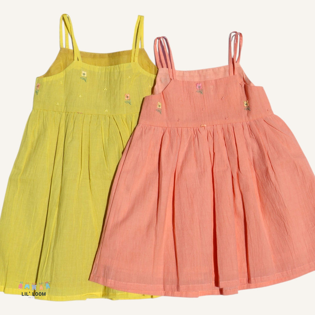Two dresses, one yellow and one pink, on a white background.